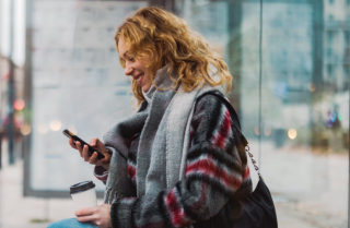 Tyttö pysäkillä katsomassa kännykkää